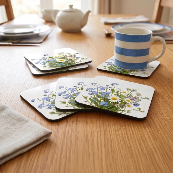 Six personalised MDF coasters arranged on a dining table with matching printed designs.